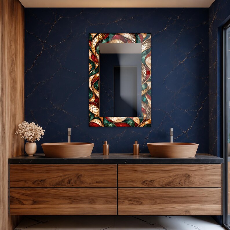 Op de afbeelding: Een rechthoekige wandspiegel met een decoratieve lijst voorzien van een kleurrijk, wervelend abstract patroon in rood-, groen- en goudtinten. De spiegel is gemonteerd boven een houten wastafelmeubel met twee ge&iuml;ntegreerde waskommen en donkere marmeren bladen.