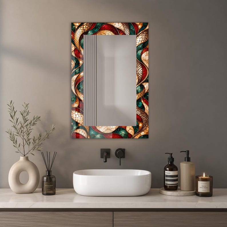 Op de afbeelding: Een rechthoekige wandspiegel met een decoratieve rand met een herhalend patroon van in elkaar grijpende, gebogen vormen in tinten dieprood, smaragdgroen en cr&egrave;me, geaccentueerd met een textuurachtig, schubachtig goud en bruin raster.