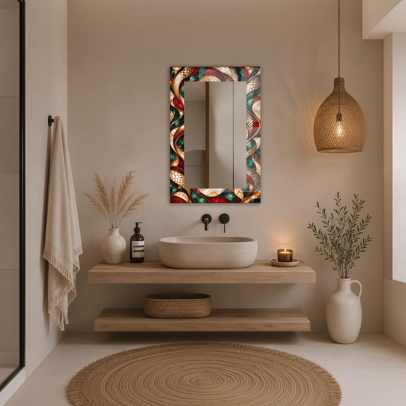 Op de afbeelding: Een rechthoekige wandspiegel met een decoratieve lijst voorzien van een levendig, meerkleurig glas-in-loodpatroon in dieprode, groenblauwe en gouden tinten, gekenmerkt door ingewikkelde, wervelende organische vormen en een glanzend, reflecterend oppervlak.