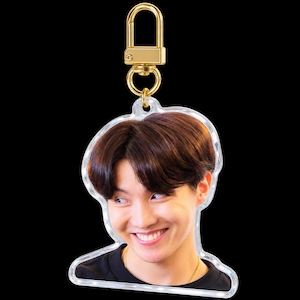 May include: A clear acrylic keychain featuring a photographic portrait of a person with dark brown hair, wearing a black shirt, and smiling. The keychain is attached to a gold-colored metal lobster clasp and a circular ring connector.