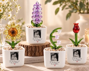 May include: Four white square ceramic planters, each containing a crystal flower and small stones. The planters feature a black and white photo of a person holding a child, with the text "Be the things you loved the most about her." and a red heart.