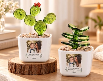 Könnte beinhalten: Zwei weiße, quadratische Keramikübertöpfe mit grünen Sukkulenten aus Glas. Jeder Übertopf zeigt ein aufgedrucktes Foto einer Person und eines Kindes mit dem Text: Behind the man I love is the amazing mother who raised him. 11.06.2026.