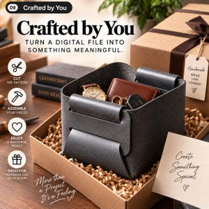 Puede incluir: Una bandeja de almacenamiento de cuero gris oscuro con lados plegados, que contiene un reloj de pulsera dorado, una cartera de cuero marrón y un llavero. La bandeja se encuentra dentro de una caja de regalo de cartón con relleno de papel y una etiqueta que dice Handmade Ideas Live Longer.