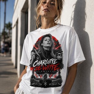Può includere: Una t-shirt bianca a maniche corte con una stampa grafica di Charlotte de Witte. Il design include diverse immagini dell'artista, effetti di luce laser rossa, il testo "CHARLOTTE DE WITTE" in bianco e rosso e "K N T X T" sotto.