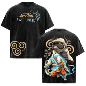 May include: A black acid-wash t-shirt featuring the Avatar The Last Airbender logo and air symbol on the front. The back displays a graphic of Aang in an orange outfit with Appa the flying bison, surrounded by swirling blue energy and gold accents.