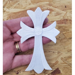 May include: White embroidered cross patch with a raised center circle.