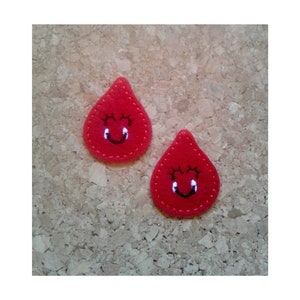 May include: Two red felt drops with embroidered smiling faces. The drops have black eyelashes and a black smile.