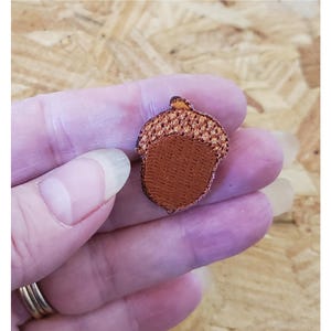May include: A small brown and orange acorn-shaped patch with a textured surface.