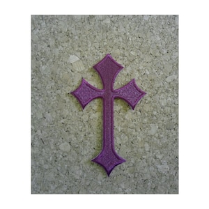 May include: Purple embroidered iron-on patch of a cross with a pointed design.