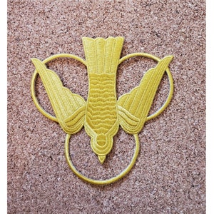 May include: A gold embroidered patch depicting a dove with outstretched wings, surrounded by three circles. The dove is a symbol of peace and the Holy Spirit.