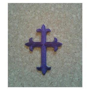 May include: Purple embroidered iron-on patch of a cross with ornate details.