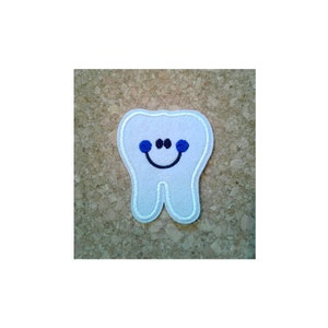May include: White felt tooth with a blue smiling face and blue eyes.