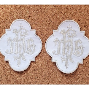 May include: Two white fabric patches with silver embroidered "IHS" lettering and a cross. The patches are shaped like a four-leaf clover.