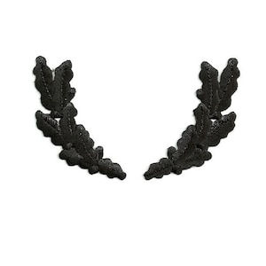 May include: Black embroidered laurel wreath design. The wreath is made of two symmetrical halves, each with three leaves.