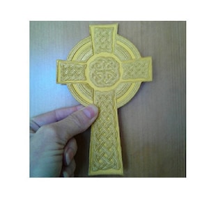 May include: A gold Celtic cross with intricate knotwork design. The cross is made of wood and has a raised, three-dimensional appearance.