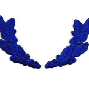 May include: Two blue embroidered fabric oak leaf wreaths. The leaves are arranged in a semi-circle shape.