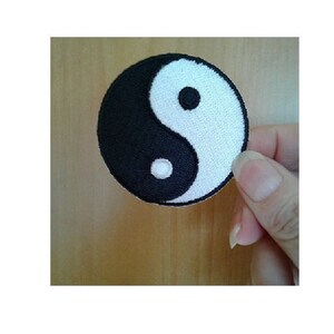 May include: A black and white yin yang symbol embroidered patch. The patch is circular and has a white background with a black yin yang symbol in the center.