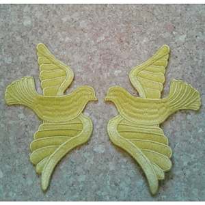 May include: Two yellow embroidered fabric doves, facing each other, with wings spread out.