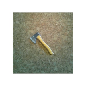 May include: A small, silver-colored axe with a yellow wooden handle. The axe is lying on a corkboard surface.