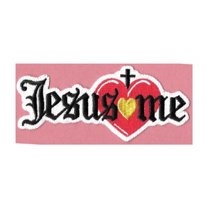 May include: White embroidered patch with the words "Jesus" and "me" in black script. A red heart with a gold heart inside and a white cross on top is between the words.