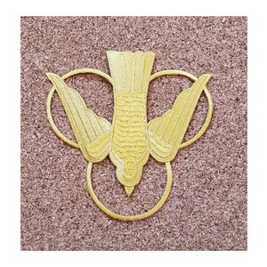 May include: A gold embroidered patch depicting a dove with outstretched wings, surrounded by three circles. The dove is a symbol of the Holy Spirit in Christianity.