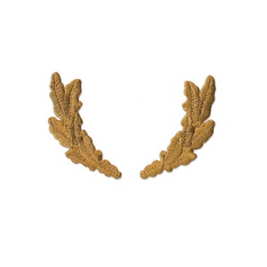 May include: Two gold embroidered laurel wreaths, each with a pointed tip, are arranged in a semi-circle shape.