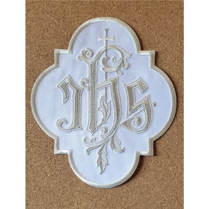 May include: White fabric patch with a silver embroidered monogram of the letters "IHS" with a cross above the letters.