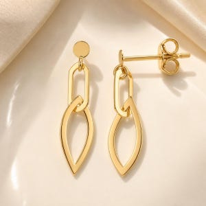 May include: A pair of gold-toned drop earrings featuring a small circular stud connected to an elongated oval link, which attaches to a pointed, leaf-shaped drop. The earrings include a standard post and butterfly back closure mechanism.