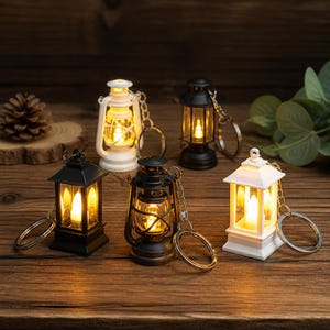 Peut inclure: Un ensemble de cinq porte-clés en forme de lanterne miniature, disponibles en noir et blanc. Chaque lanterne possède des parois en plastique transparent et une lumière LED interne émettant une lueur jaune chaude. Chaque unité inclut une chaînette.