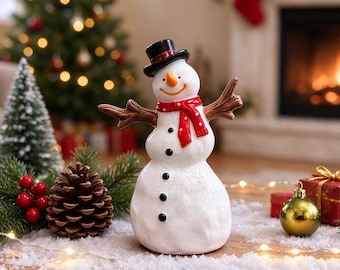 Peut inclure: Une figurine de bonhomme de neige blanc avec un haut-de-forme noir, un nez en forme de carotte orange et une écharpe rouge à pois blancs. Il possède des bras en forme de branches brunes et quatre boutons noirs sur le devant.