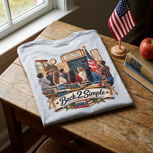 Puede incluir: Una camiseta gris claro con un gráfico de una escena de aula con estudiantes, una bandera estadounidense y el texto "Learn Today, Lead Tomorrow" y "Back 2 Simple" en una pancarta. El diseño incluye libros, un reloj y una pizarra.