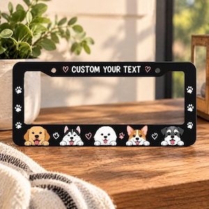 May include: A black rectangular license plate frame featuring the text CUSTOM YOUR TEXT flanked by two small hearts. The bottom border displays five illustrated dog faces and paw prints along the sides, all set against a solid black background.