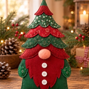 May include: A fabric Christmas tree ornament shaped like a gnome with a layered green and red patterned fabric top, a large peach-colored nose, a red corduroy beard, and three white buttons. It features a small jute loop for hanging.