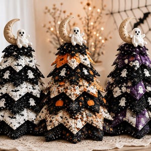 May include: Three fabric-covered cone-shaped trees featuring quilted layers with Halloween patterns including ghosts, bats, pumpkins, and spiderwebs. Each tree is topped with a small plush white ghost sitting on a beige crescent moon.
