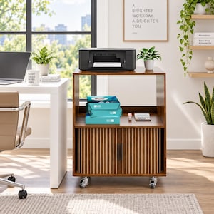 May include: A brown wooden printer stand with a top surface, an open middle shelf, and a lower cabinet with two vertical slatted doors. The unit features four silver caster wheels, a black printer on top, and blue paper reams on the middle shelf.
