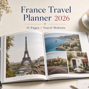 May include: An open France Travel Planner 2026 book featuring the text France Travel Planner 2026 and 15 Pages + Travel Website. The pages display photographs of the Eiffel Tower, a coastal landscape, a lavender field, and a French cafe exterior.
