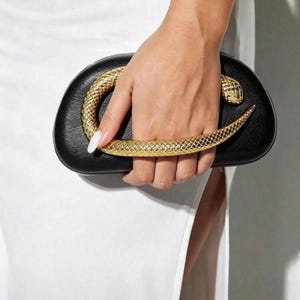 Peut inclure: Une pochette noire de forme arrondie et lisse, dotée d'une poignée métallique dorée en forme de serpent enroulé. La poignée en forme de serpent s'étend sur le devant du sac, avec la tête positionnée sur le côté droit et la queue sur le côté gauche.