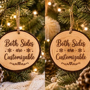 May include: A round wooden slice ornament with bark edges, hanging from a jute twine loop. The front surface features dark laser-engraved text that reads Both Sides are Customizable, accented with two snowflake icons and a small heart flourish.