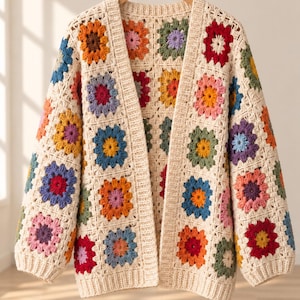 May include: A long-sleeve cardigan constructed from cream-coloured yarn featuring a multi-coloured granny square pattern. The garment includes a ribbed cream border along the front opening, cuffs, and hem, showcasing various floral-inspired motifs.