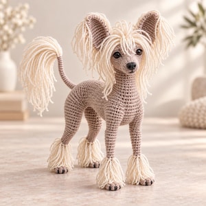 May include: A crocheted Chinese Crested dog figurine featuring a light brown body with cream-colored yarn fringe on the ears, tail, and paws. The dog has dark brown eyes and a black nose, with a standing posture and detailed yarn texture throughout.
