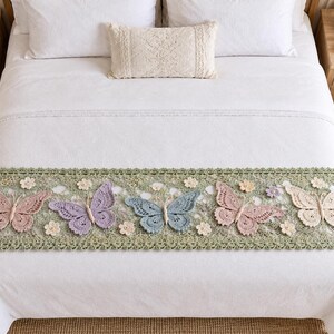May include: A rectangular crochet bed runner featuring a sage green base with an intricate lace border. The runner is decorated with five large, three-dimensional butterflies in shades of dusty pink, lavender, light blue, and cream, accented by small flowers.