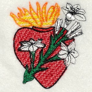 May include: Embroidered image of a red heart with flames on top and white flowers with green stems.