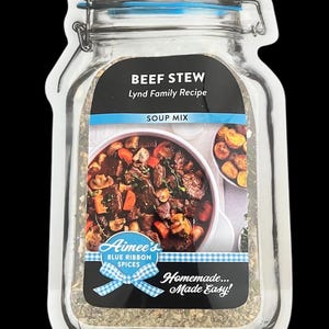 May include: Aimee's Blue Ribbon Spices Beef Stew Soup Mix in a clear glass jar with a blue lid. The jar is on a white background and has a picture of a bowl of beef stew with potatoes and carrots. The text on the jar reads "BEEF STEW Lynd Family Recipe SOUP MIX Homemade... Made Easy!"