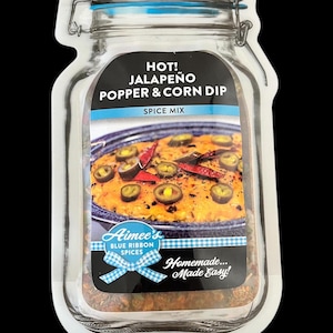 May include: Aimee's Blue Ribbon Spices Hot! Jalapeño Popper & Corn Dip Spice Mix. A clear glass jar with a blue lid and a white label. The label has a picture of a casserole dish with jalapeño peppers and corn. The text "Homemade... Made Easy!" is on the label.