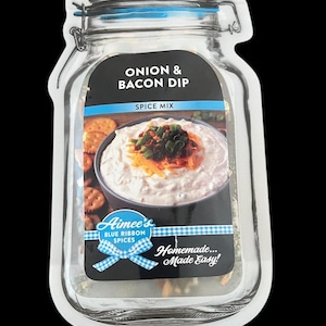 May include: Aimee's Blue Ribbon Spices Onion & Bacon Dip spice mix in a clear glass jar with a blue lid. The jar has a label with a picture of a bowl of dip with crackers. The label also says "Homemade... Made Easy!"