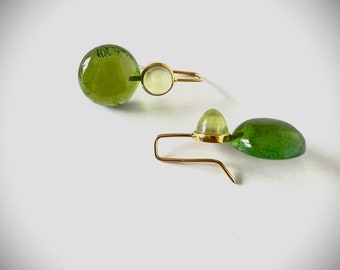 May include: A pair of gold earrings with green and white gemstone accents. The earrings feature a teardrop-shaped green gemstone and a round white gemstone.