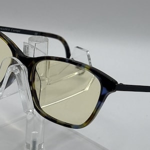 May include: Tortoiseshell-patterned glasses with light yellow-tinted lenses. The frames feature a dark brown and black mottled design with thin, straight black temples. The interior of the temple arm displays the text "TOM HARRIS | europe".