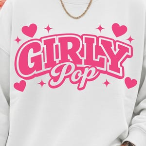 以下が含まれることがあります： 鮮やかなピンク色の「GIRLY Pop」の文字がプリントされた白いスウェットシャツ。ピンクのハートと星が周りに散りばめられています。カジュアルな普段着に最適です。