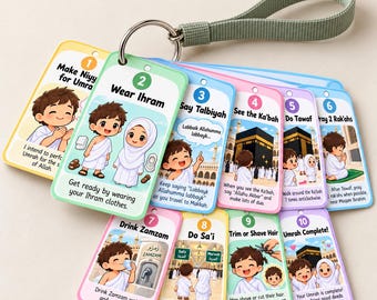 May include: A set of ten colourful, numbered educational cards attached to a silver metal ring with a sage green fabric strap. Each card features cartoon illustrations and text explaining the steps of Umrah, from making Niyyah to completion.