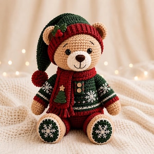 May include: A crocheted teddy bear wearing a dark green and red stocking cap with a pom-pom, a red scarf with a small green tree button, and a dark green sweater featuring white snowflake patterns and two small wooden buttons on the chest.
